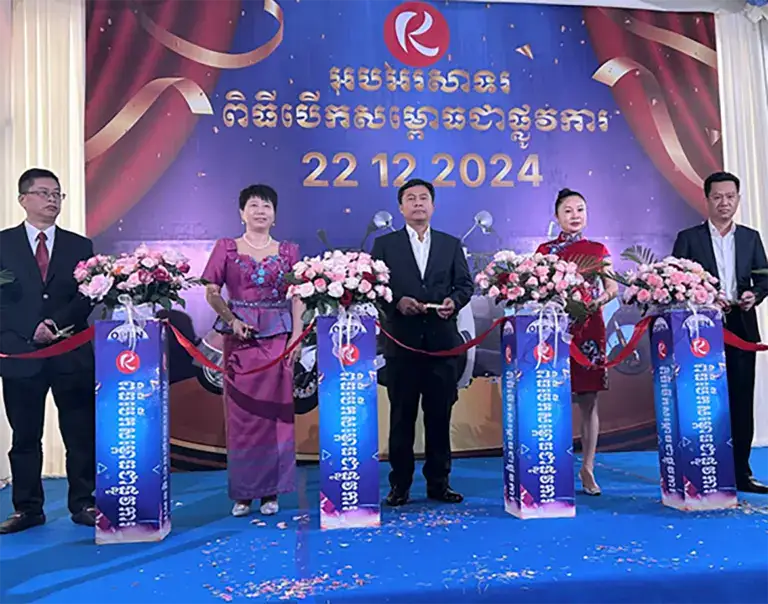 A group of five people dressed professionally standing behind floral podiums at a formal event.