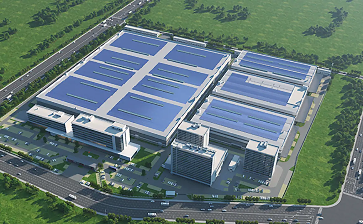 Aerial view of a large industrial complex with multiple buildings and solar panels, surrounded by greenery and roads, showcasing modern infrastructure and sustainable energy solutions.