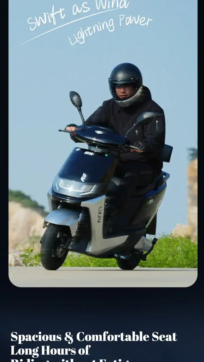 A rider on a modern scooter wearing a helmet, riding on a clear day with a blue sky. The scooter features a spacious seat and wind protection, ideal for urban commuting and short trips.